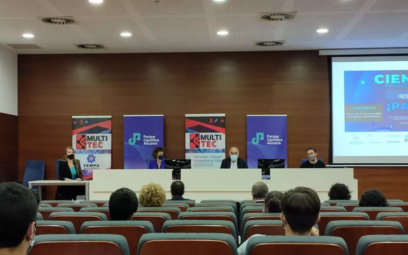 Mesa de ponentes del II Cienciathon con los roll-ups de MultitecUA y del Parque Científico